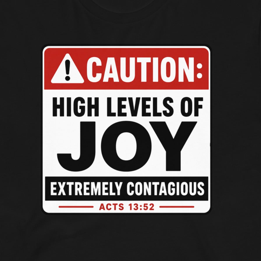 A black t-shirt featuring a printed graphic of a warning sign that reads 'CAUTION: HIGH LEVELS OF JOY EXTREMELY CONTAGIOUS ACTS 13:52' in red, white, and black.